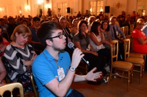 a civil servant holding a microphone asking a question during a conference