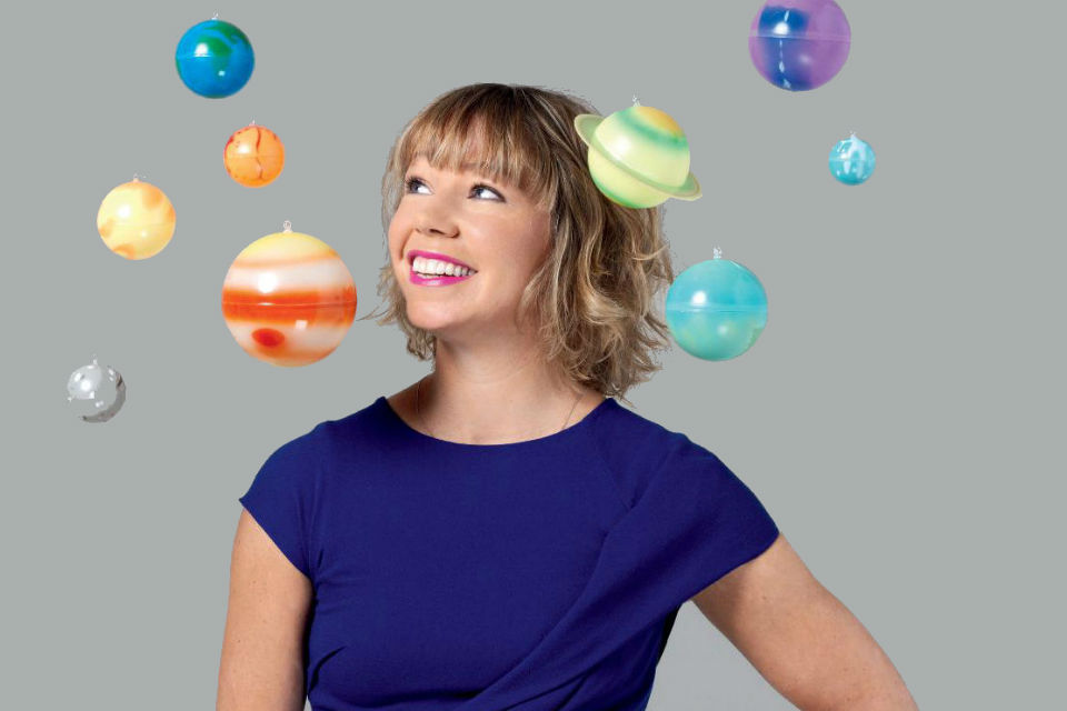 Photo of Dr Alice Bunn surrounded by planets from a model solar system
