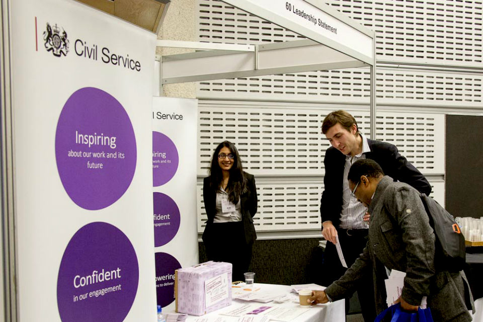 Leadership Statement stand with banners on left and a man and two women looking at literature.