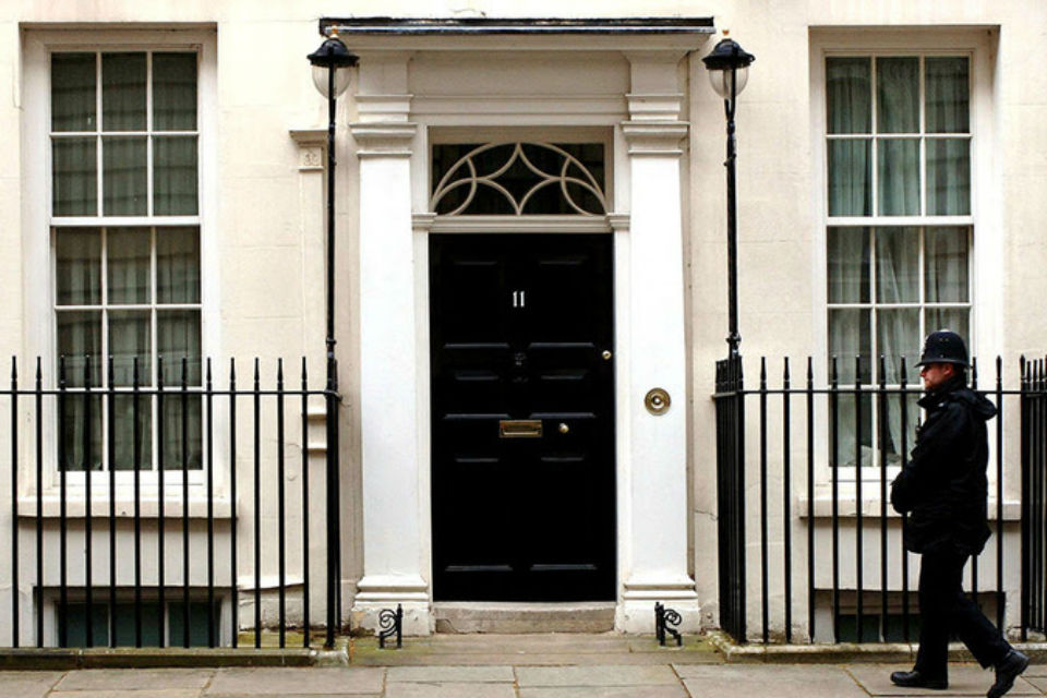 Exterior and front door of 11 Downing Street, with a policeman on the right.
