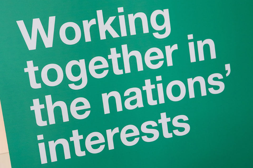 Banner with legend: Working together in the nations' interests