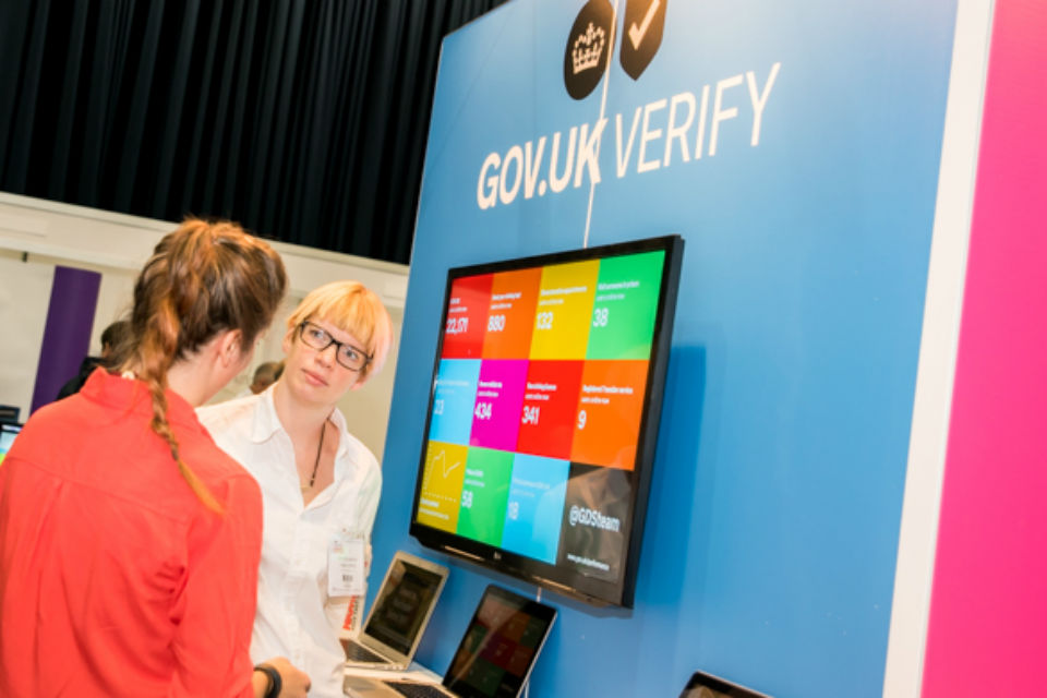 Two women speaking in front of display stand and screen