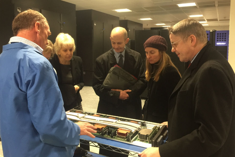 Jeremy Heywood, right, being shown computing equipment by a blue-overalled technician, while four others, three women and a man, look on.