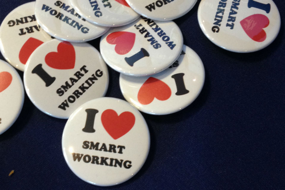 Pile of badges on a dark blue table. The badges read 'I heart smart working'