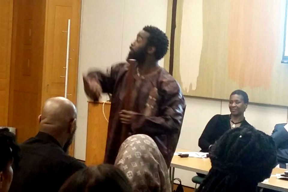 Poet and storyteller performs in front of seated audience