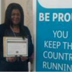 Woman holding certificate next to banner