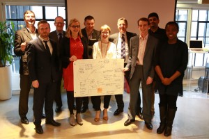 Group shot with ten men and women in front of projection screen, with two women (centre front) holding flowchart.