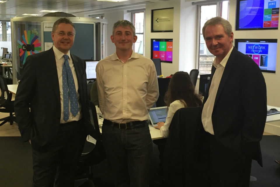 Three men in a line with office background