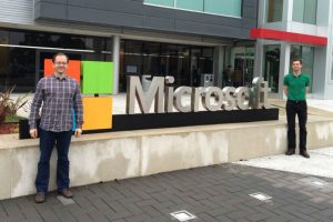 Two men standing by Microsoft sign