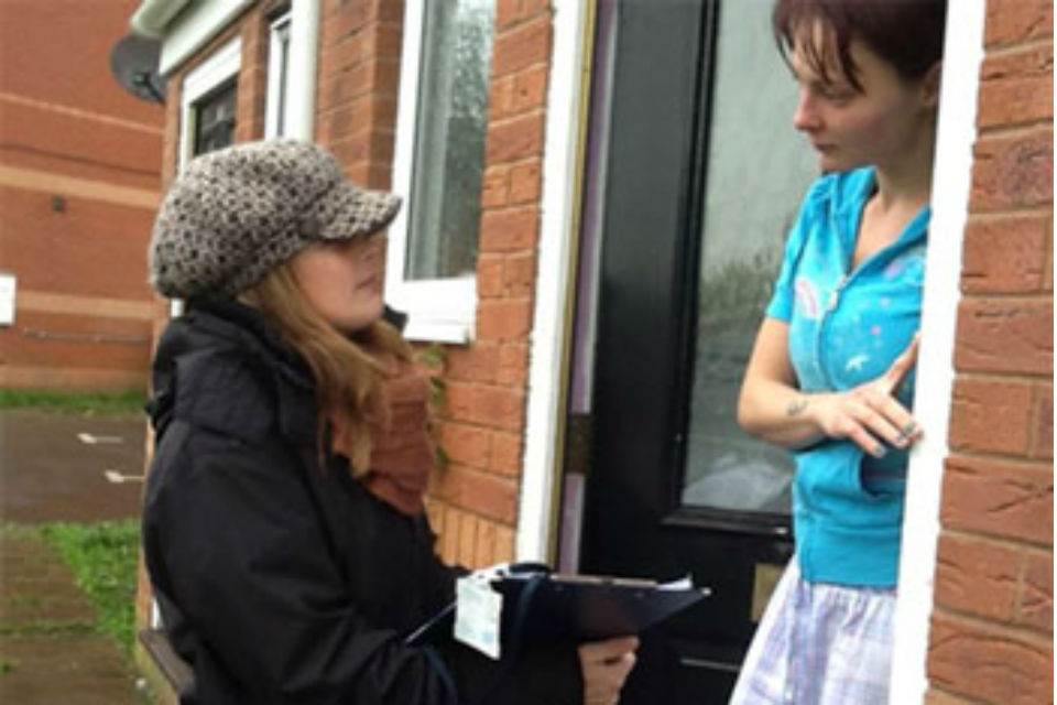 Woman in hat with clipboard speaking to another woman on their doorstep