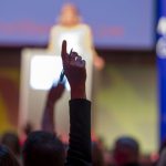 Man's arm raised to ask question at conference