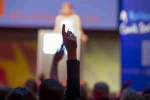 Man's arm raised to ask question at conference