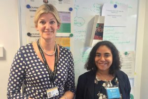 One tall woman and one short woman in front of notice board