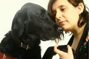 Woman holding paw of black labrador dog