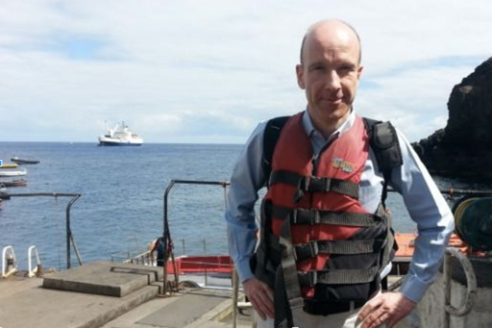 Man on jetty with sea and boats in background