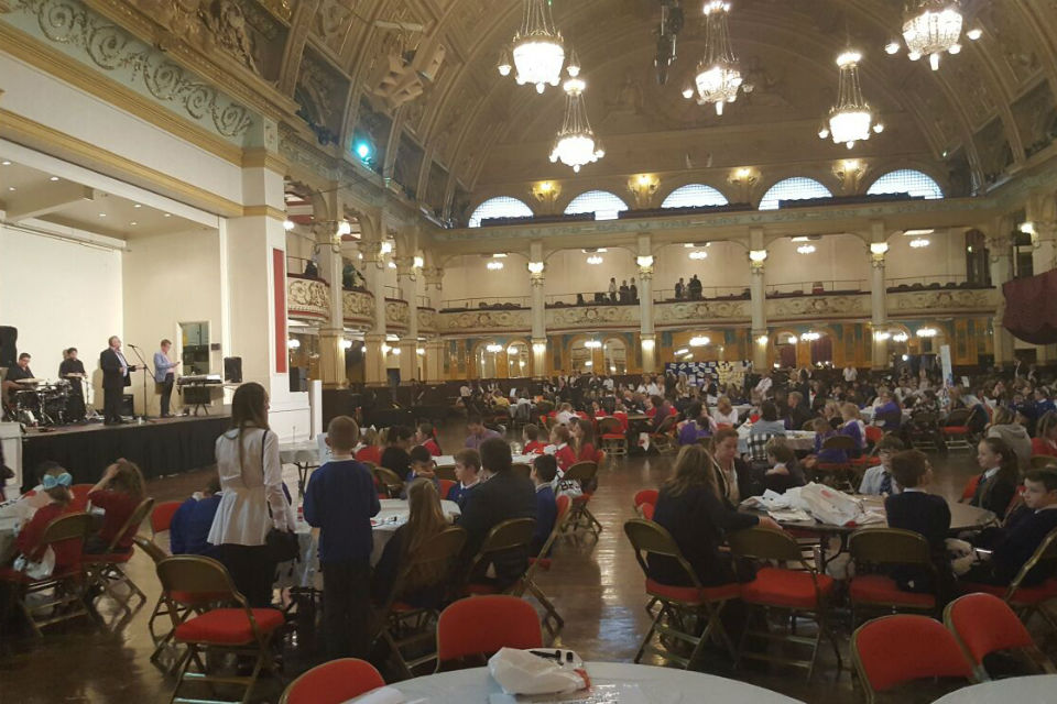 Large dance hall with band on stage and audience at tables