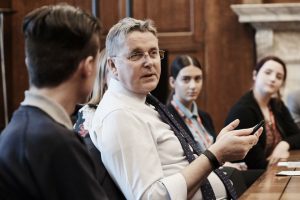 Man in shirt and ties talking at table with young people