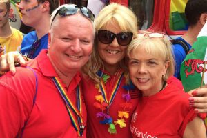 Man and two women at Pride event in red shirts