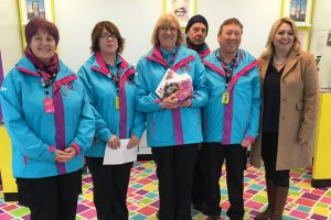 Group of six men and women, four in sky blue jackets