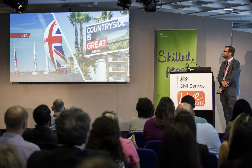 Man on podium and audience watching film on screen