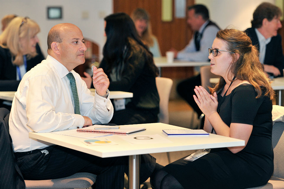 Man and woman face each other across a table in mentoring session