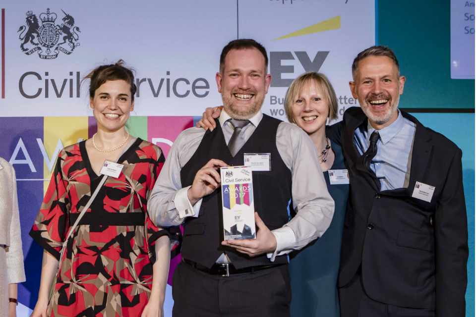 Two men and two women with award