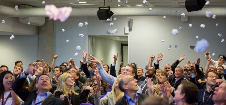 People in conference throwing crumpled post-it notes in the air