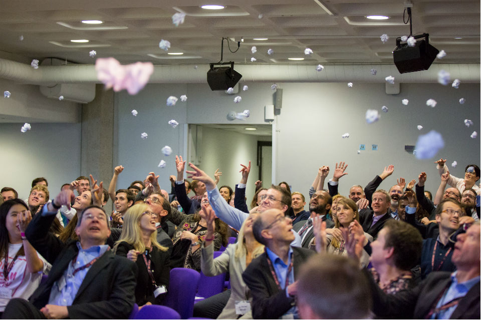 People in conference throwing crumpled post-it notes in the air