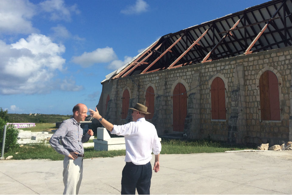 Two men talking in front of storm-damaged building