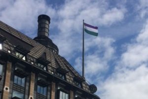 Women's suffrage flag flying from mast over building