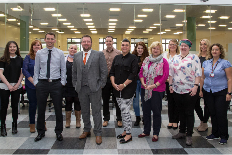 Group of men and women standing in an office space