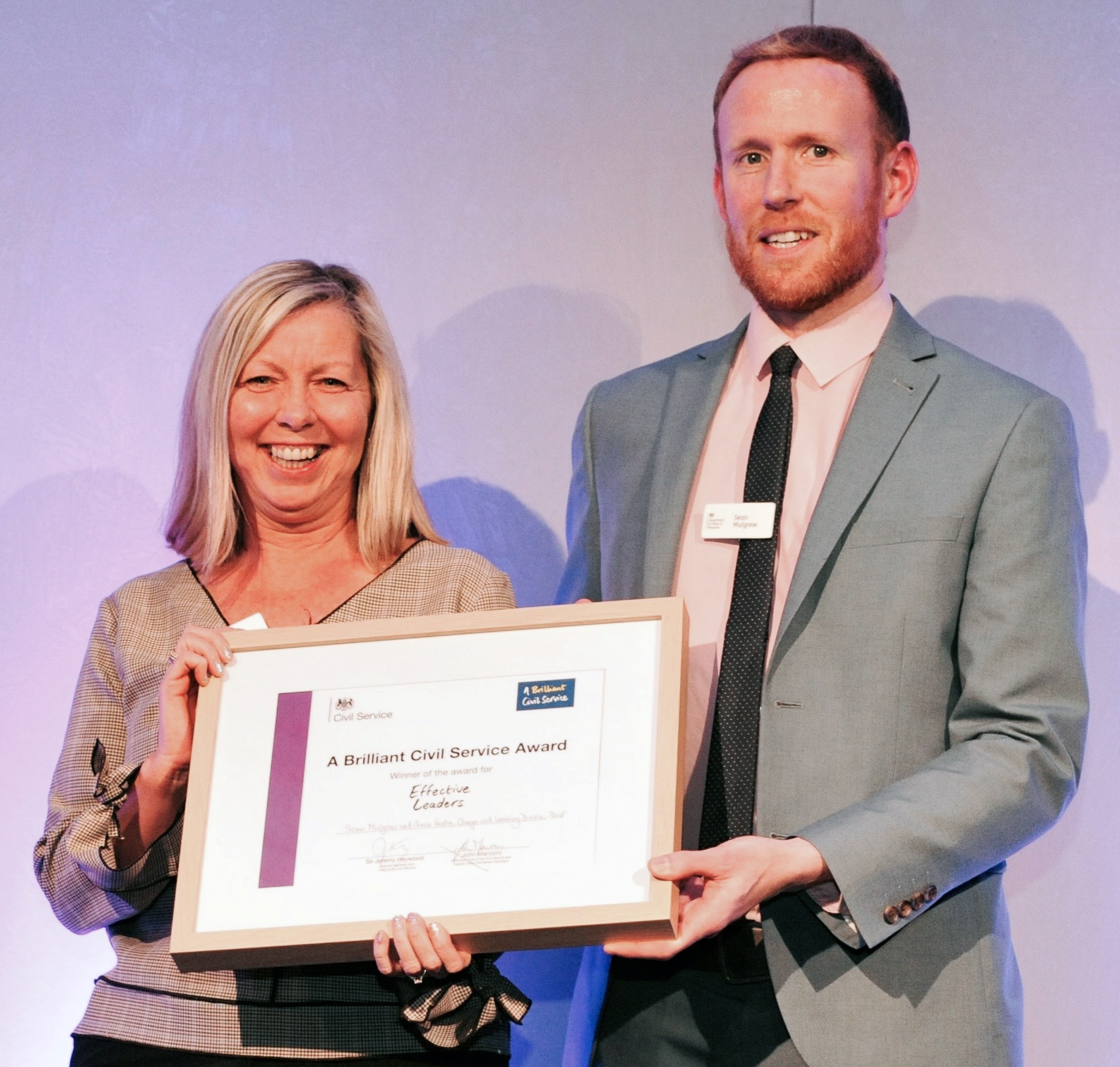 Man and woman holding framed award certificate