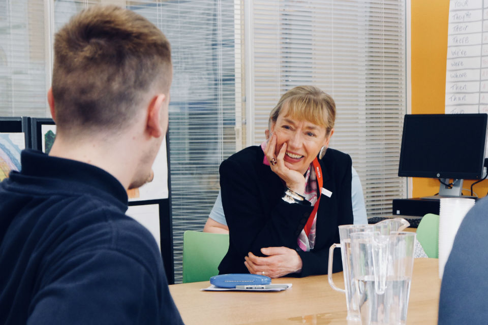 Woman at table in conversation with young man in young offenders institution