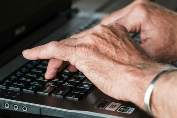 Image showing a man's hands typing on the keyboard of a laptop computer.