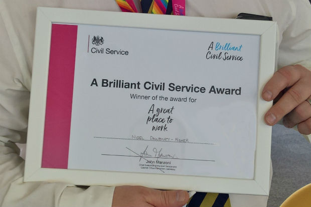 Hands holding the framed certificate of 'A Brilliant Civil Service' Award for 'A great place to work'