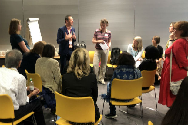 Man and woman standing and conducting a learning session, with participants seated around