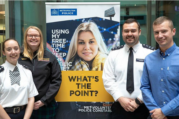 Special constables standing beside a banner promoting special constable roles in the Metropolitan Police