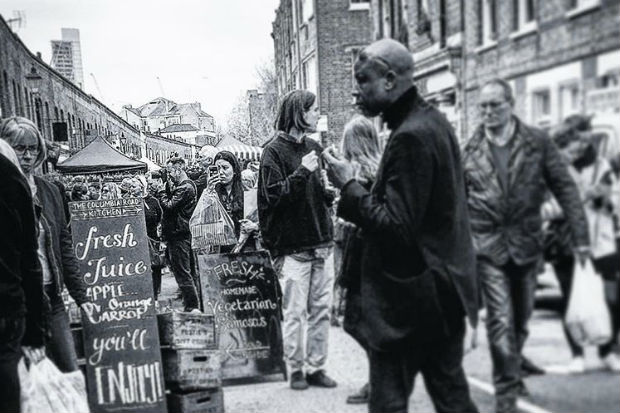 Brian Stanislas walking past market stalls in Brick Lane East London