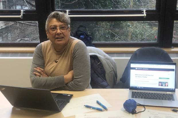 Woman working at a desk with laptop showing the Civil Service Jobshare Finder web site