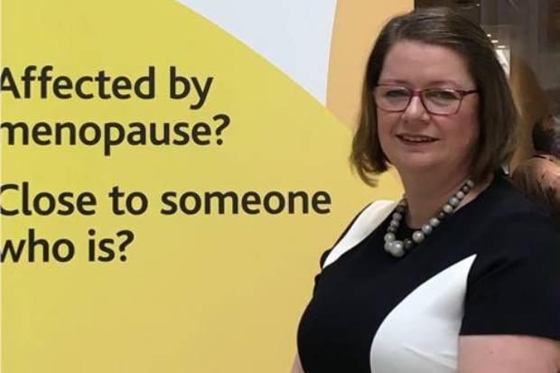 Karen Canner in front of a banner displaying the words: Affected by menopause? Close to someone who is?