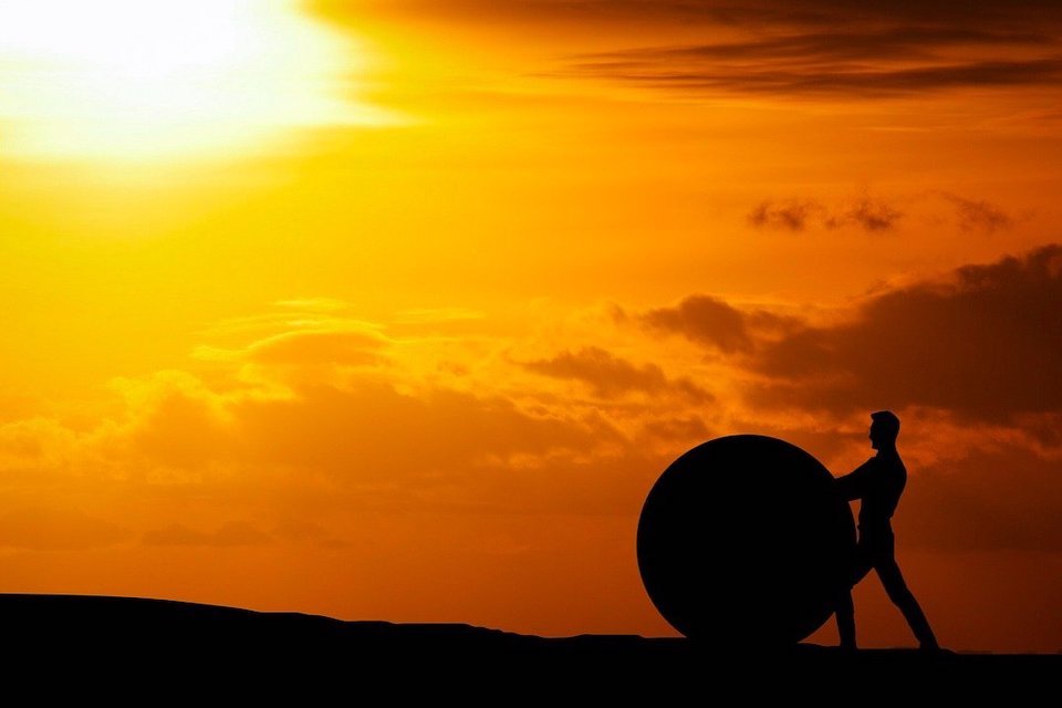 Image of a person pushing a boulder uphill