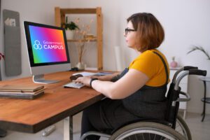 Young disabled woman in glasses sitting in wheelchair and entering login while preparing to start e-learning class at home