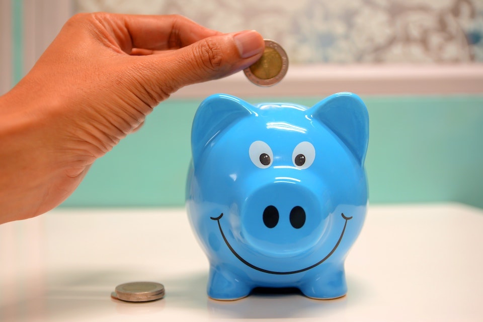 Image of person putting coins into a piggy bank