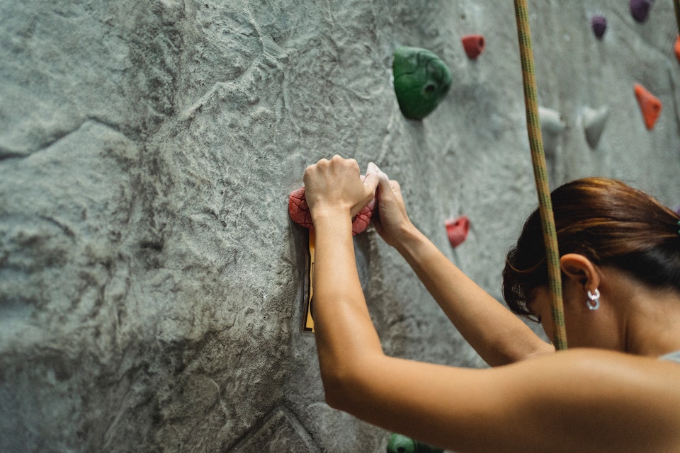 A woman grips a climbing wall