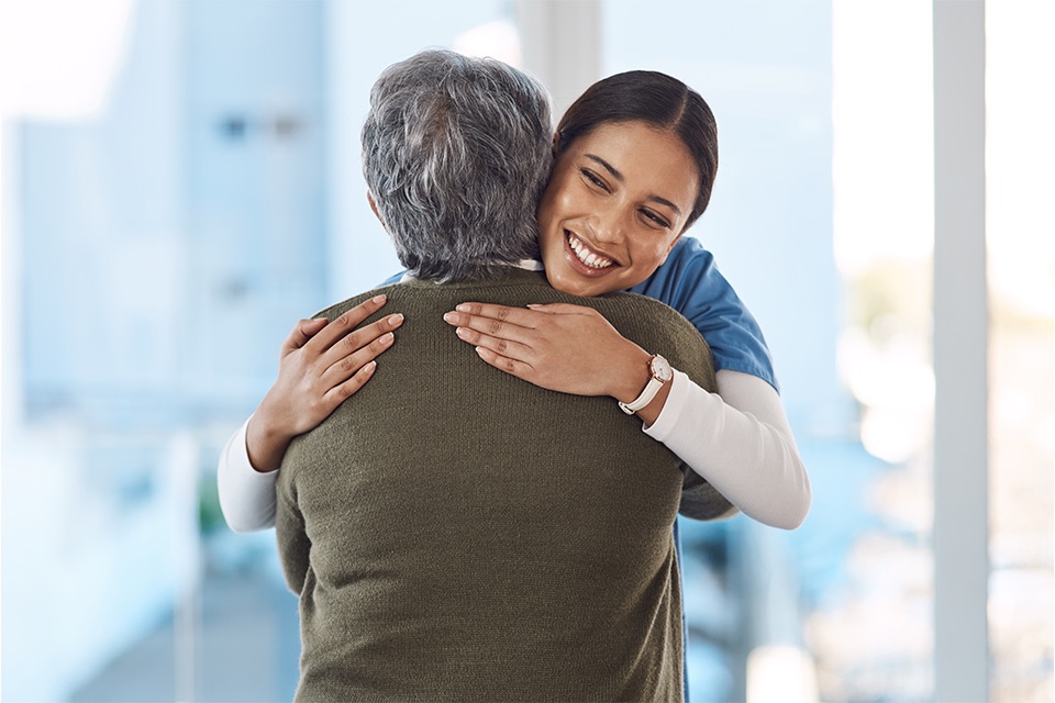 Younger woman carer hugs older person