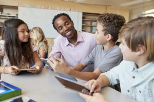 Teacher helping school kids using tablet computers in class