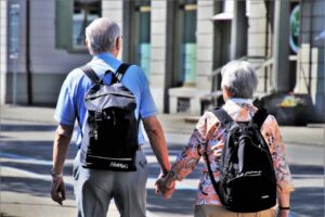 A retired couple hand in hand, walking