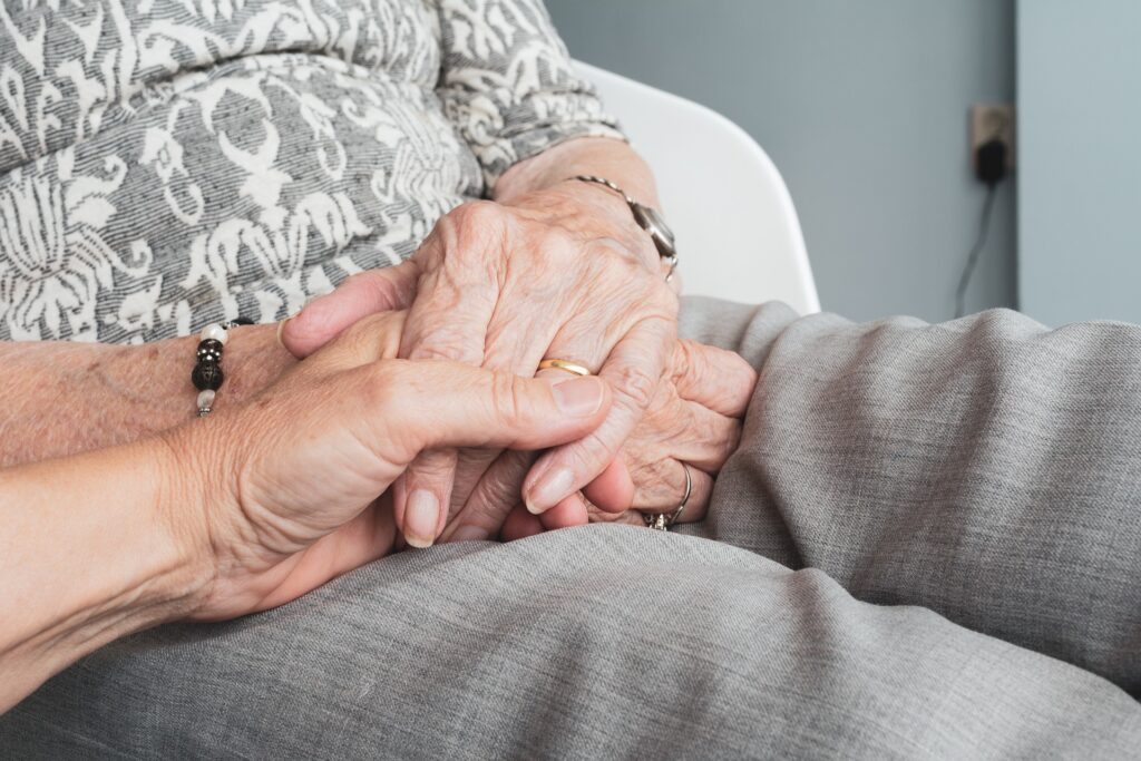 Image of a carer clasping hands with a loved one
